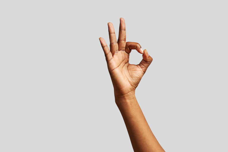 Hand making an OK sign on a plain background