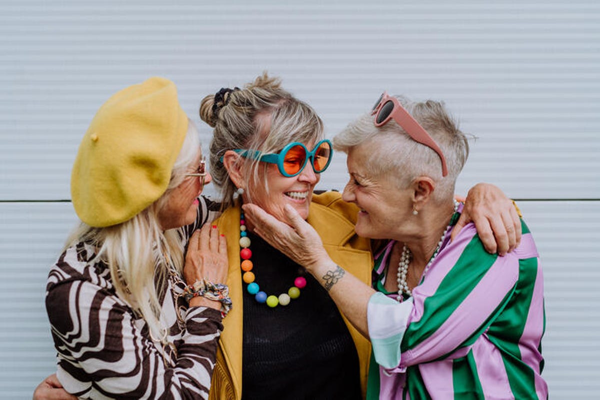 Three happy old women in colorful clothes.