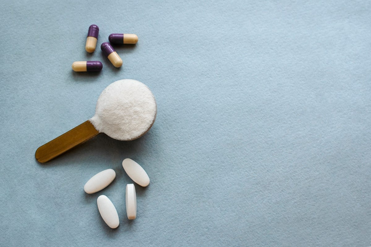 Three types of collagen in tablets and capsules in powder on a gray background